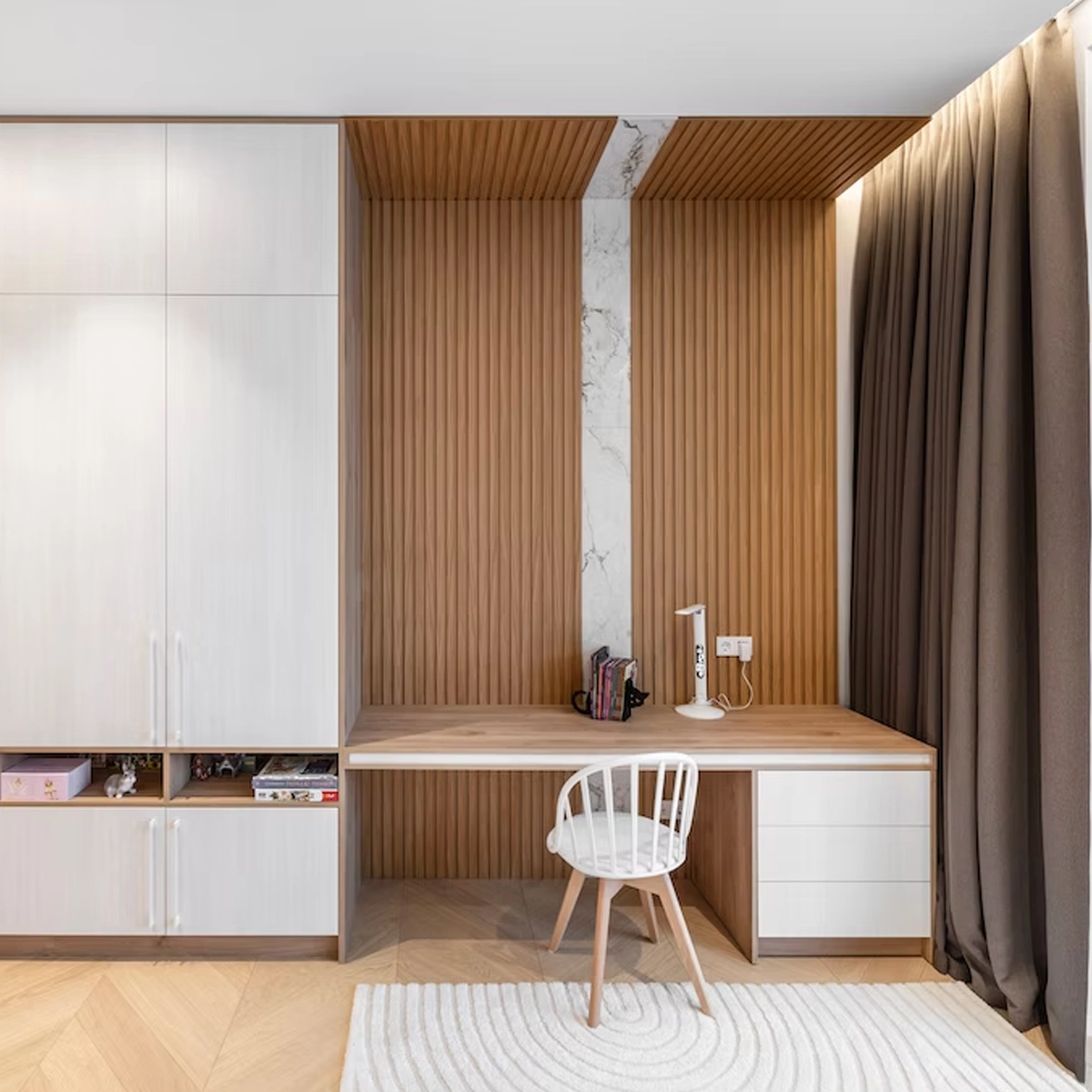 Möbel nach Maß im Jugendzimmer: links eine weiße Schrankwand mit offenen Bücherfächern, rechts eine Schreibtischnische mit Holzlamellen an Wand und Decke, durchgehender Holzplatte und Schubladenblock in Weiß.